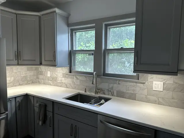 Kitchen with dark gray cabinetry, white quartz counters and a marble subway tile backsplash